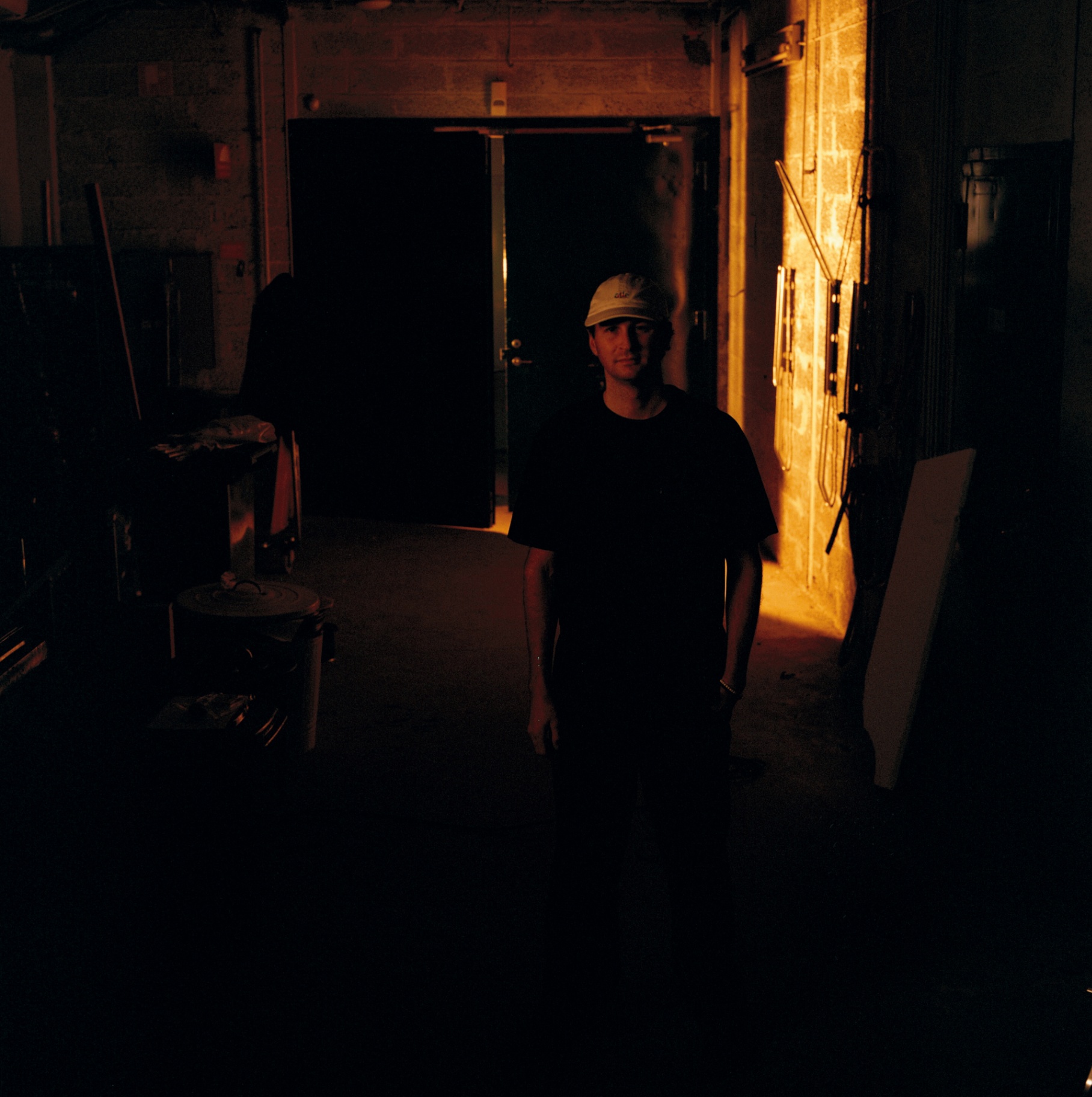 Standing in a dark backstage corridor lit by a single warm lamp